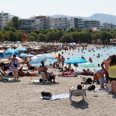 Λουόμενοι σε παραλία απολαμβάνουν ήλιο και θάλασσα