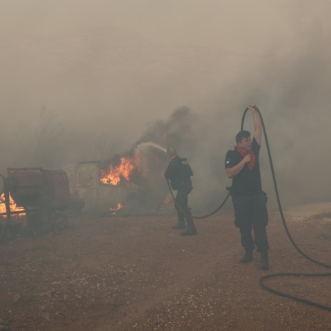 Πυροσβέστες και εθελοντές με μάνικα στα χέρια επιχειρούν για την κατάσβεση πυρκαγιάς