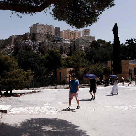 Πολίτες με ομπρέλες και καπέλα προστατεύονται από την ηλιακή ακτινοβολία