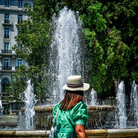 Γυναίκα με καπέλο μπροστά από το σιντριβάνι στην πλατεία Συντάγματος