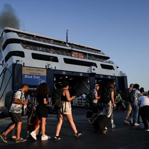 Πολίτες με βαλίτσες ετοιμάζονται για την επιβίβασή του σε πλοίο στο λιμάνι του Πειραιά