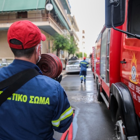 Πυροσβέστης με μάνικα ανά χείρας δίπλα σε όχημα
