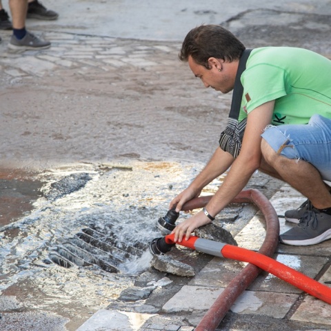 Άνδρας πάνω από φρεάτιο στο οποίο πέφτουν τα νερά μετά τη θραύση αγωγού στη Θεσσαλονίκη