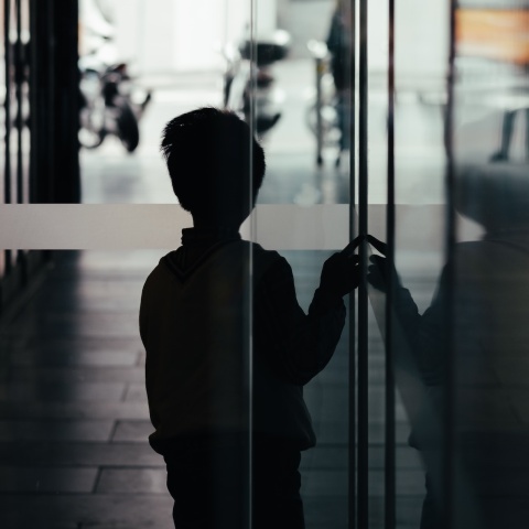 Παιδί σε σκοτεινό διάδρομο φαίνεται να φοβάται να βγει στο φως - Εικόνα που παραπέμπει σε κακοποίηση και bullying