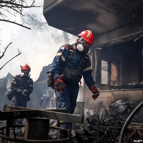 Πυροσβέστες περπατούν δίπλα σε καμένα σπίτια