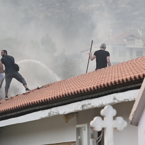 Εθελοντές με τη μάνικα νερού επιχειρούν για την κατάσβεση της πυρκαγιάς