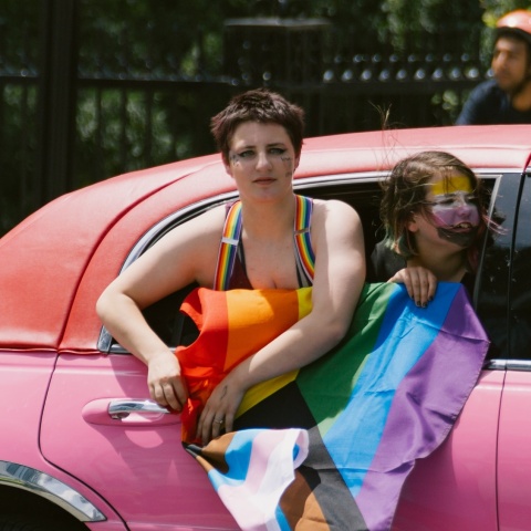 Άτομο μέσα σε αυτοκίνητο κρατά σημαία της ΛΟΑΤΚΙ+ κοινότητας