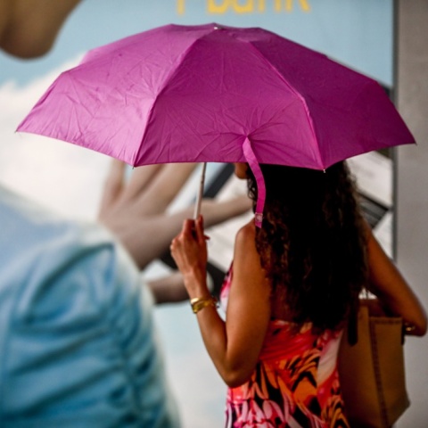 Γυναίκα κρατά ομπρέλα για να προστατευτεί από τη βροχή