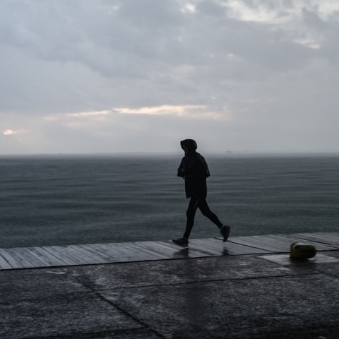 Πολίτης με αδιάβροχο τρέχει στην παραλία της Θεσσαλονίκης