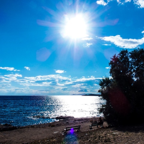 Ήλιος λαμπερός και λίγα σύννεφα πάνω από παραλία