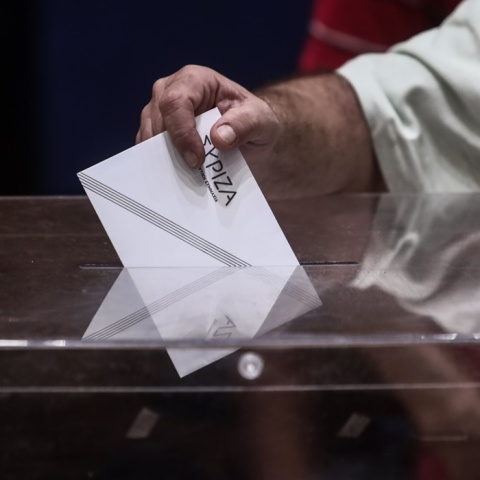 Χέρι άνδρα ρίχνει το ψηφοδέλτιο με το λογότυπο του ΣΥΡΙΖΑ σε κάλπη