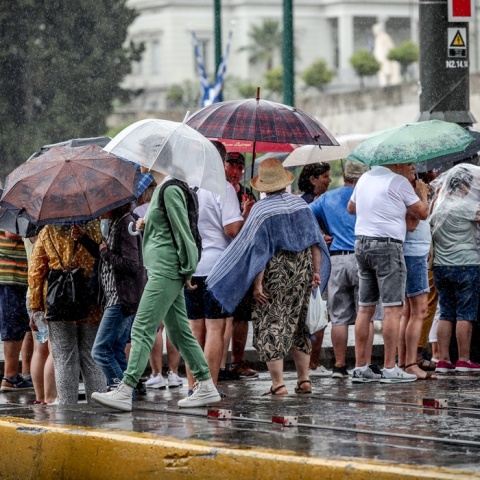 Πολίτες στο κέντρο της Αθήνας προσπαθούν να προστατευτούν από καταιγίδα