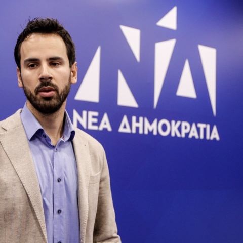 Ο Νίκος Ρωμανός μπροστά από το λογότυπο της Νέας Δημοκρατίας 