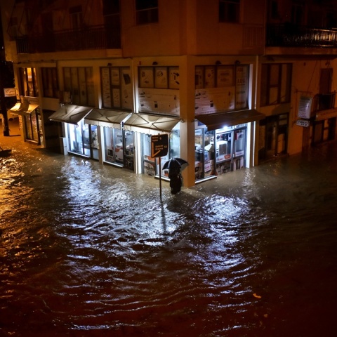 Άνδρας στον Βόλο περπατά με ομπρέλα σε πλημμυρισμένο δρόμο ενώ το νερό του φτάνει μέχρι το γόνατο