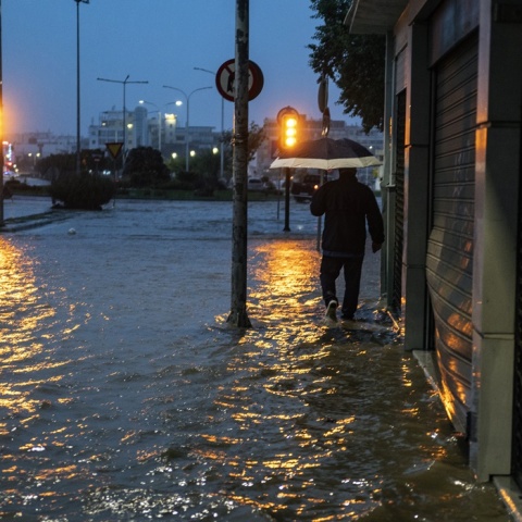 Άνδρας περπατά σε πλημμυρισμένο δρόμο στον Βόλο