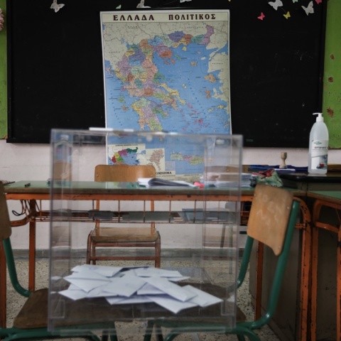Κάλπη με ψηφοδέλτια μπροστά από χάρτη της Ελλάδας σε εκλογικό τμήμα - σχολική αίθουσα