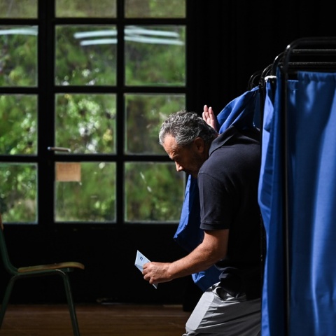 Ψηφοφόρος βγαίνει από το παραβάν κρατώντας στα χέρια του το ψηφοδέλτιο