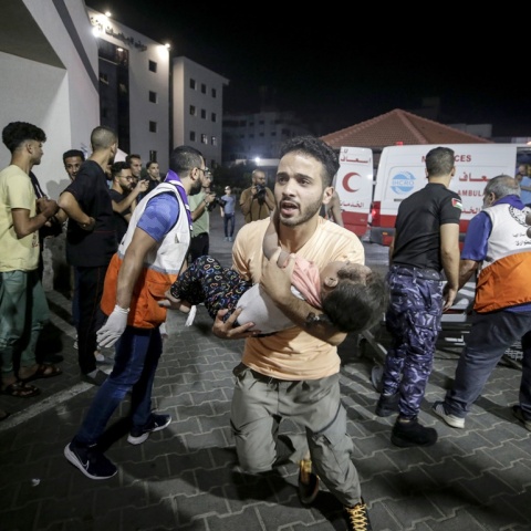 Άνδρας μεταφέρει ένα παιδί στα χέρια του στο νοσοκομείο στη Γάζα