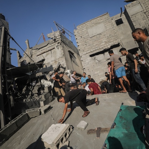 Πολίτες δίπλα σε κατεστραμμένο κτίριο στη Γάζα