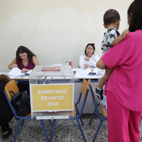 Γυναίκα κρατά το παιδί της στην αγκαλιά και προσέρχεται στην κάλπη για τις Αυτοδιοικητικές Εκλογές 2023