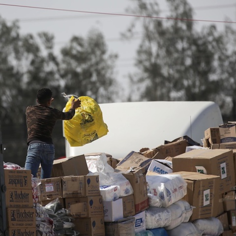 Άνδρας κρατά μία σακούλα πάνω σε φορτηγό με ανθρωπιστική βοήθεια για τη Γάζα