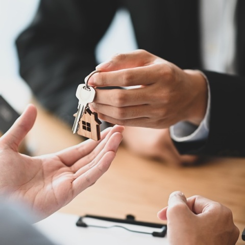 Άτομο δίνει τα κλειδιά σπιτιού σε άλλο άτομο που είναι γυρισμένο πλάτη στον φακό