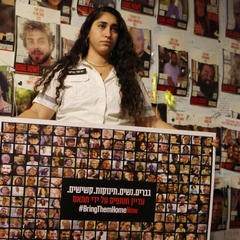 Γυναίκα κρατά πανό με τις φωτογραφίες ομήρων της Χαμάς