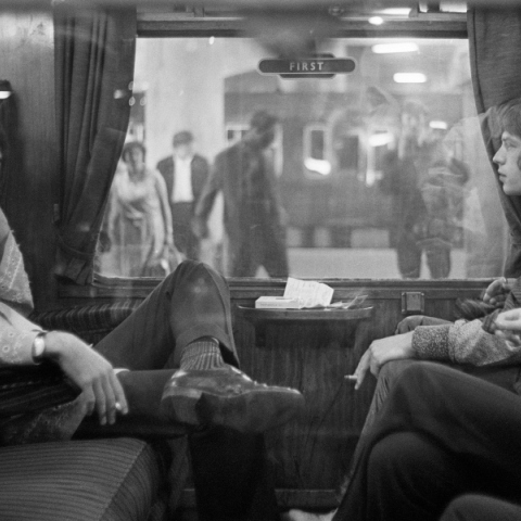 Ο Paul McCartney των Beatles και ο Mick Jagger των Rolling Stones κάθονται ο ένας απέναντι από τον άλλο σε ένα τρένο στο σταθμό Euston, περιμένοντας την αναχώρηση για το Bangor,