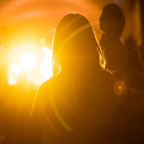 Η σκιά κοριτσιού διακρίνεται σε φώτα χρώματος που παραπέμπει σε φωτιά