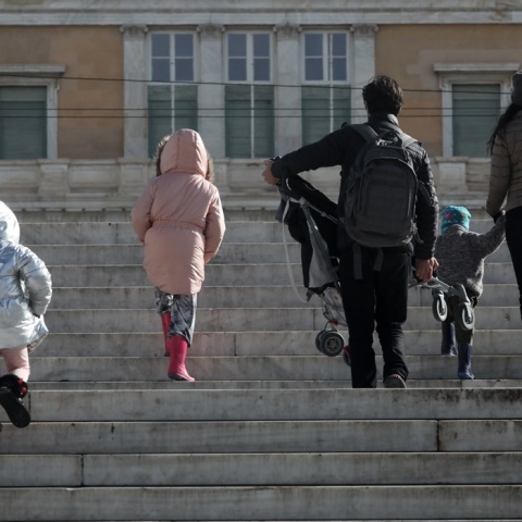 Πολίτες με παιδιά και με χοντρά ρούχα και σκουφιά για το κρύο ανεβαίνουν τα σκαλιά στην πλατεία Συντάγματος