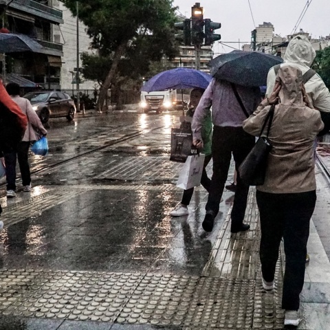 Πολίτες με ομπρέλες εν μέσω βροχής