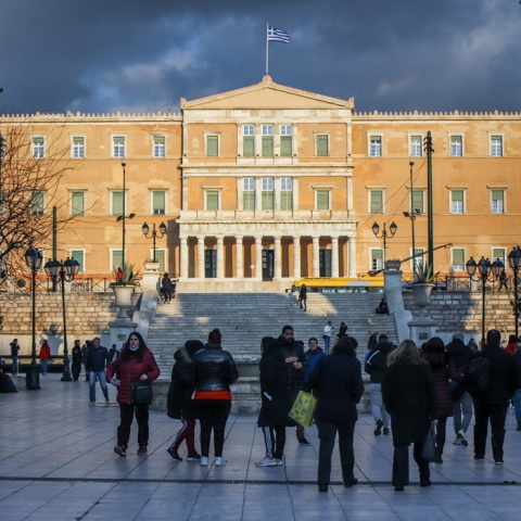 Πολίτες περπατούν στην πλατεία Συντάγματος με φόντο τη Βουλή των Ελλήνων