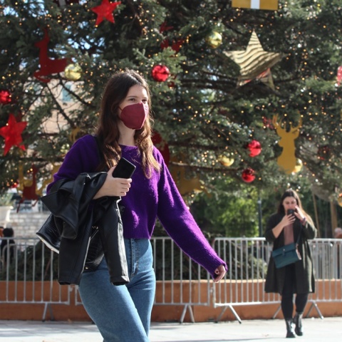 Κοπέλα με μάσκα προστασίας από τον κορωνοϊό μπροστά από το χριστουγεννιάτικο δέντρο στο Σύνταγμα