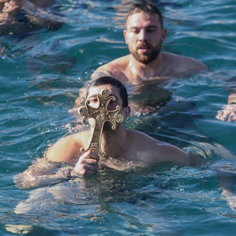 Νεαρός κρατά τον Σταυρό που μόλις έχει πιάσει από τα παγωμένα νερά της θάλασσας