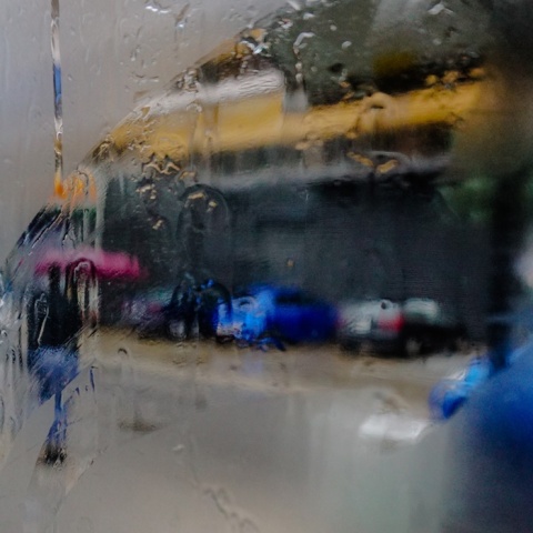 Άτομο με ομπρέλα σε λήψη από θολωμένο και βρεγμένο τζάμι