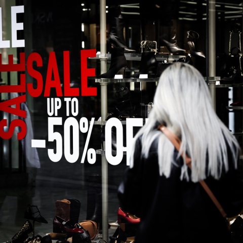 Γυναίκα πλάτη στον φακό μπροστά από κατάστημα υπόδησης με εκπτώσεις 