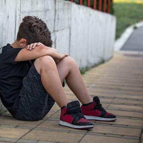 Ανήλικος με το πρόσωπο χωμένο στα πόδια του - Εικόνα που παραπέμπει σε bullying