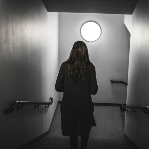 Γυναίκα με γυρισμένη πλάτη σε σκοτεινό διάδρομο