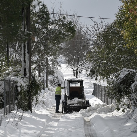 Μηχάνημα για τη διάνοιξη δρόμων από τα χιόνια και δίπλα ο χειριστής του