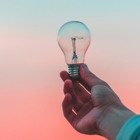 Χέρι κρατά μία λάμπα  με φόντο τον ουρανό