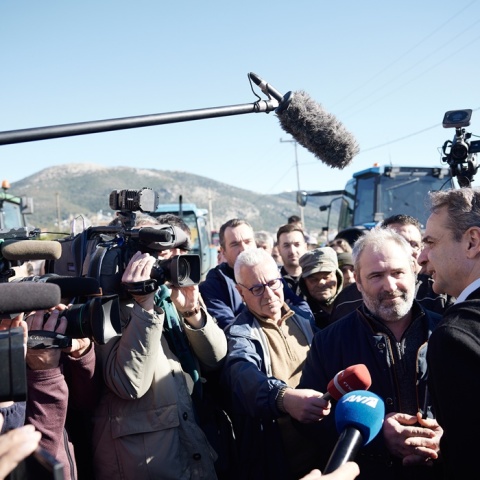 Ο Κυριάκος Μητσοτάκης κάνει δηλώσεις στα τηλεοπτικά συνεργεία ενώ στο βάθος της φωτογραφίας υπάρχουν παραταγμένα τρακτέρ