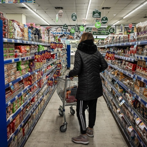 Γυναίκα με καρότσι του σούπερ μάρκετ σε διάδρομο με γλυκίσματα 