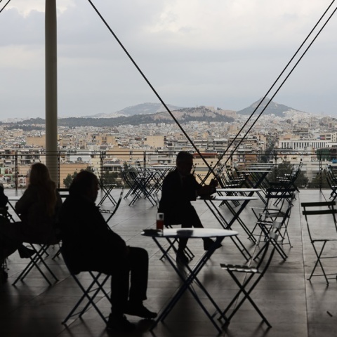 Συννεφιά και άτομα που κάθονται σε τραπεζάκια στο Κέντρο Πολιτισμού Ίδρυμα Σταύρος Νιάρχος