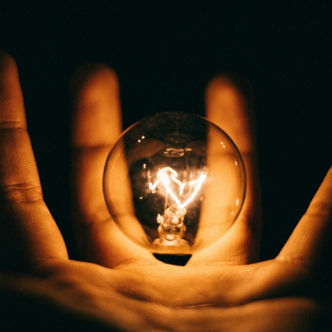 Αναμμένη λάμπα ανάμεσα στα δάχτυλα ατόμου