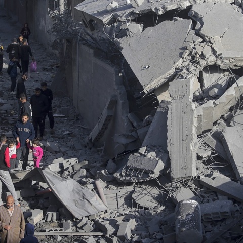 Πολίτες κρατούν από το χέρι μικρά παιδιά, περνώντας από τα συντρίμμια 