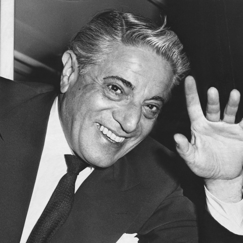 Ο Αριστοτέλης Ωνάσης με πλατύ χαμόγελο, υψώνει το χέρι του για να χαιρετίσει