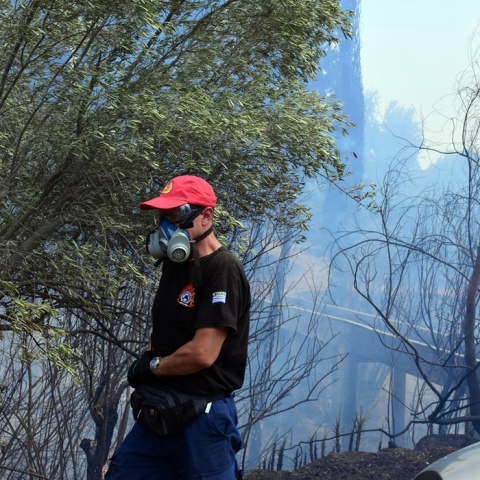 Πυροσβέστης με μάσκα για τους καπνούς κρατά τη μάνικα