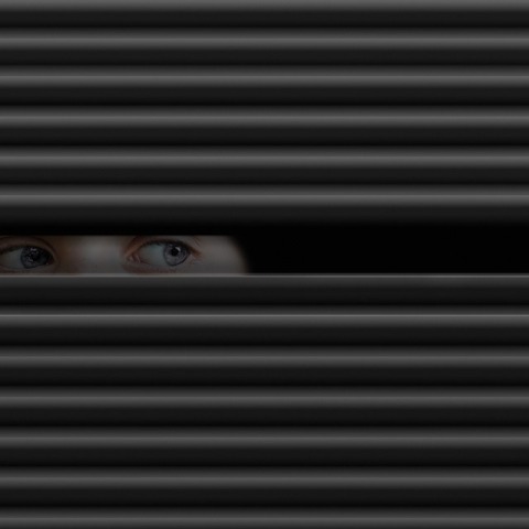 Τα μάτια παιδιού που είναι κρυμμένο πίσω από γρίλλιες