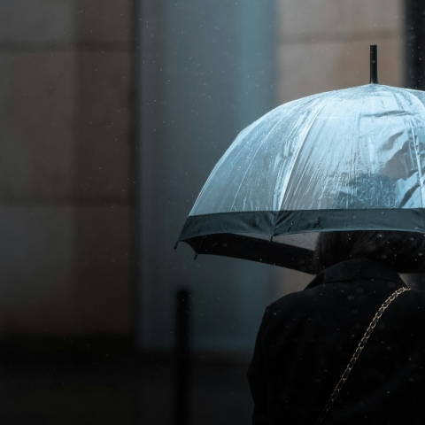 Γυναίκα κρατάει ομπρέλα μέσα στη βροχή