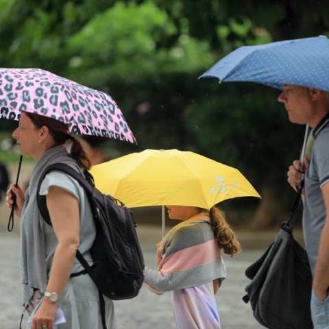 Ζευγάρι με το παιδί τους κρατούν ομπρέλες για να προστατευτούν από τη βροχή